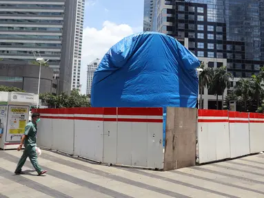 Warga berjalan dekat proyek pembangunan Tugu Sepeda di  kawasan Jenderal Sudirman, Jakarta, Rabu (22/9/2021). Dinas Perhubungan DKI Jakarta memastikan pembangunan Tugu Sepeda masih berlanjut, dan pembangunnya hingga saat ini telah mencapai 90 persen. (Liputan6.com/Herman Zakharia)