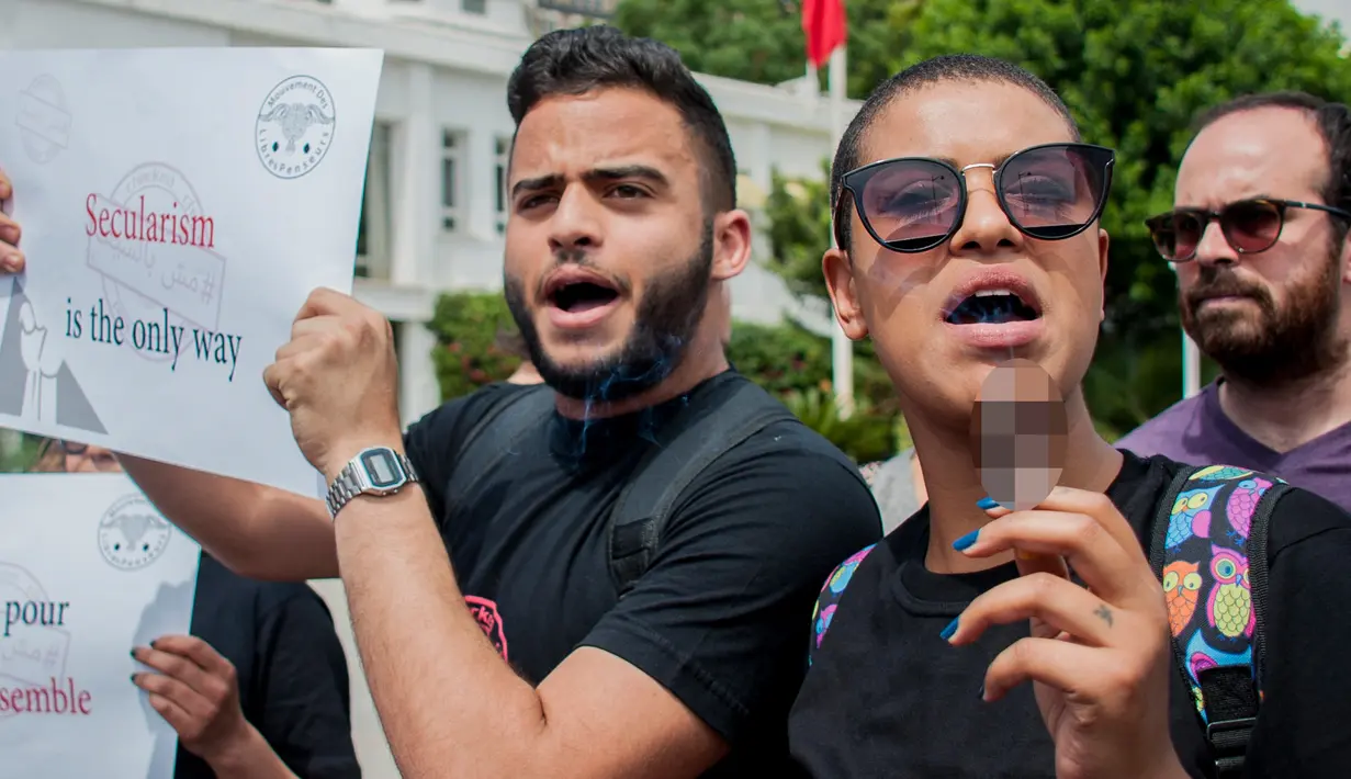 Seorang wanita Tunisia memegang sebatang merokok selama protes terhadap pemilik restoran dan bar yang menutup tokonya selama puasa bulan suci Ramadan di Tunis, Tunisia, (27/5). (AP Photo / Hassene Dridi)