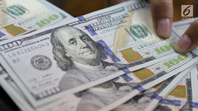 Petugas memperlihatkan uang pecahan dolar Amerika di salah satu gerai penukaran mata uang di Jakarta, Jumat (18/5). Pagi ini, nilai tukar rupiah melemah hingga sempat menyentuh ke Rp 14.130 per dolar Amerika Serikat (AS). (Liputan6.com/Immanuel Antonius)
