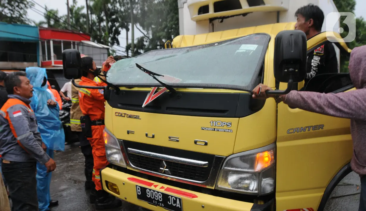 Petugas mengevakuasi truk boks yang rusak parah akibat tertimpa pohon tumbang di Jalan Padjajaran, Kota Tangerang Selatan, Banten, Sabtu (5/3/2022). Pengendara yang terluka karena tertimpa pohon tumbang dibawa ke RSUD Tangerang Selatan. (merdeka.com/Arie Basuki)