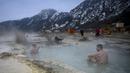 Orang-orang menikmati air panas di mata air mineral alami pada hari musim dingin di dekat desa Rupite, Bulgaria (2/2/2022). Penduduk setempat percaya bahwa air mineral menyembuhkan banyak penyakit dan gangguan. (AFP/Nikolay Doychinov)