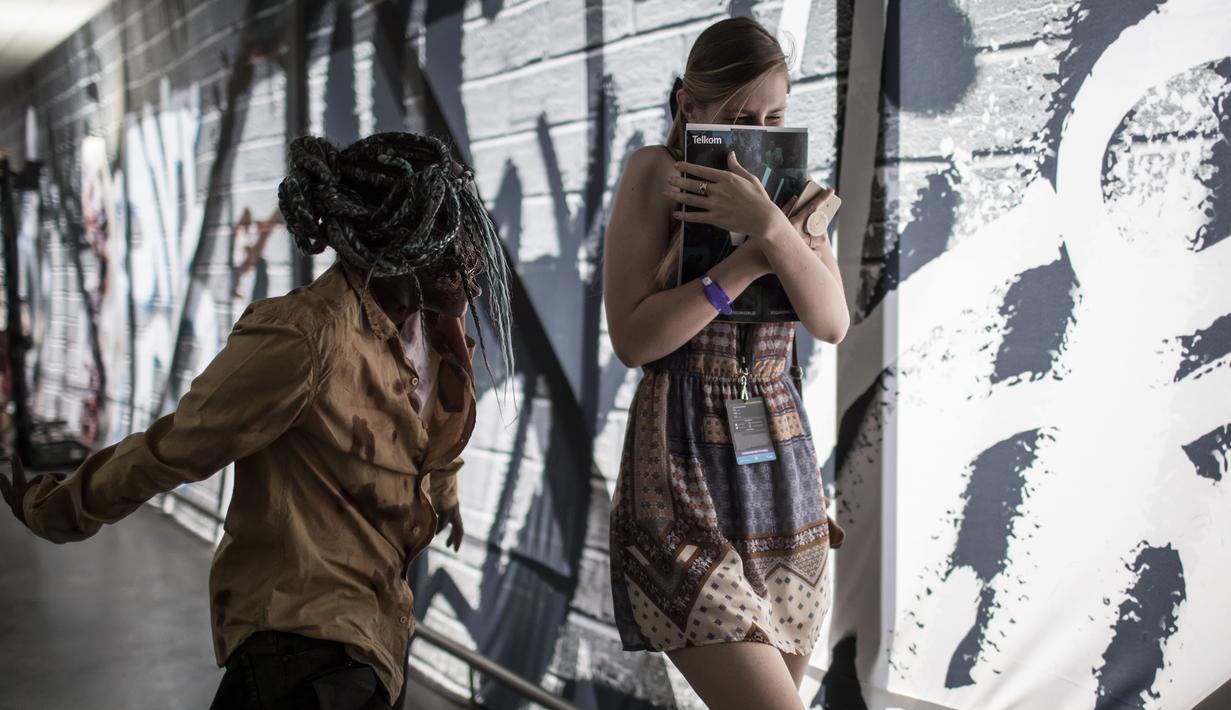 Cosplayer menggenakan kostum zombie menakuti pengunjung selama International Comic Con di Kyalami Race Course, Johannesburg, Afrika Selatan (14/9). Comic Con digelar pada tahun 1970. (AFP Photo/Marco Longari)