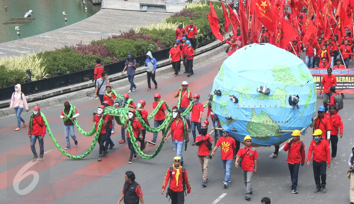 Massa buruh dari KASBI membawa gurita raksasa, bola dunia dan tikus pada peringatan May Day di Bundaran HI, Jakarta, Senin (1/5). Replika gurita itu dianggap simbol penghisap sumber daya alam yang ada di Indonesia. (Liputan6.com/Angga Yuniar)