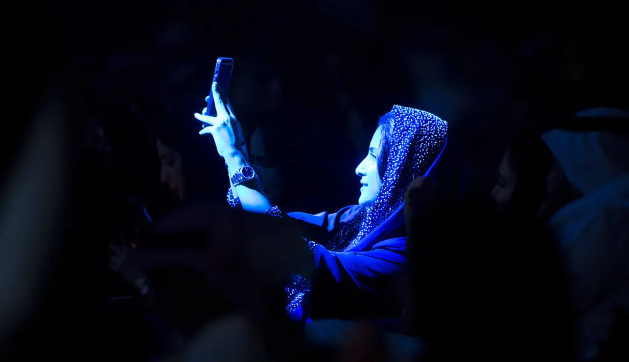Seorang wanita yang telah divaksinasi virus corona merekam penyanyi terkemuka Saudi Mohammed Abdu saat ia tampil di Super Dome yang baru dibangun, di Jeddah, Arab Saudi (8/7/2021). (AP Photo/Amr Nabil)