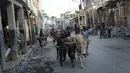 Para pria menggembalakan sapi di sepanjang jalan di Jeremie, Haiti, empat hari setelah kota itu diguncang gempa berkekuatan 7,2 pada Rabu (18/8/2021). Korban jiwa akibat gempa bumi dahsyat yang melanda Haiti Sabtu pekan lalu terus bertambah menjadi 1.941 orang.  (AP/Matias Delacroix)