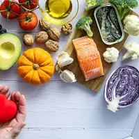 Sebuah tangan memegang benda berbentuk hati dengan bahan makanan di sekitarnya (Foto Dok: Freepik/corazzaphotos).