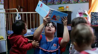 Seorang guru TK, Noelia Garella membacakan buku ke anak-anak saat bertugas di TK Jeromito, Cordoba, Argentina (24/10). Noelia 31 tahun merupakan penderita down syndrome pertama yang menjadi guru TK. (AFP Photo/Diego Lima)