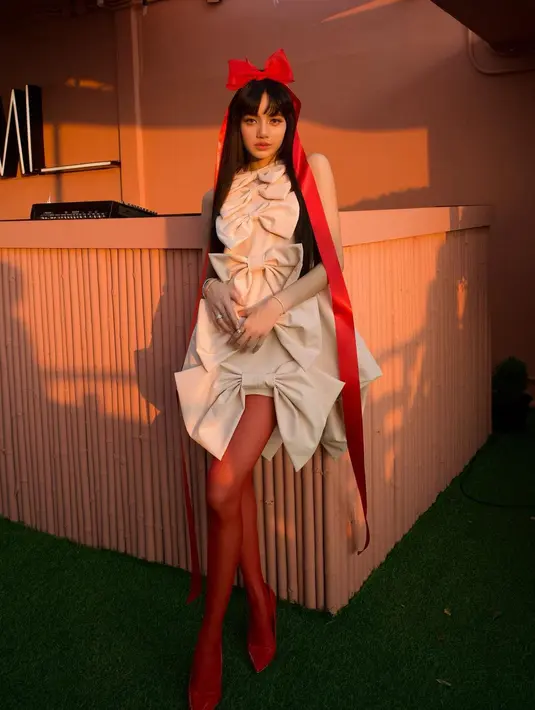 Penampilannya kian menarik dengan pita rambut besar, stocking, dan heels yang serba merah.  [Foto:IG/lalalalias_m].