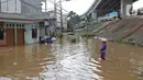 Seorang pria berdiri di tengah banjir yang merendam kawasan Cipinang Melayu, Jakarta Timur, Jumat (19/2/2021). Banjir di kawasan tersebut akibat curah hujan yang tinggi dan meluapnya air dari Kali Sunter. (Liputan6.com/Herman Zakharia)