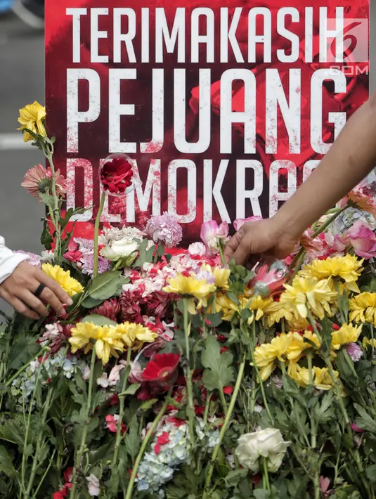 Pengunjung car free day meletakan bunga yang diberikan oleh anggota TKN Milenial Jokowi-Ma'ruf dalam kegiatan tabur bunga di Bundaran HI, Jakarta, Minggu (28/4/2019). Aksi tersebut sebagai bentuk duka atas meninggalnya 272 petugas KPPS dalam Pemilu 2019. (Liputan6.com/Faizal Fanani)
