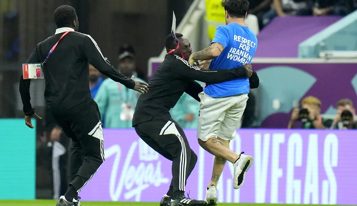 Petugas saat menangkap seorang pria yang masuk ke lapangan dengan membaw abendera pelangi selama pertandingan grup H Piala Dunia 2022 antara Portugal dan Uruguay, di Stadion Lusail di Lusail, Qatar, Senin, 28 November 2022. (AP Photo/Petr David Josek)