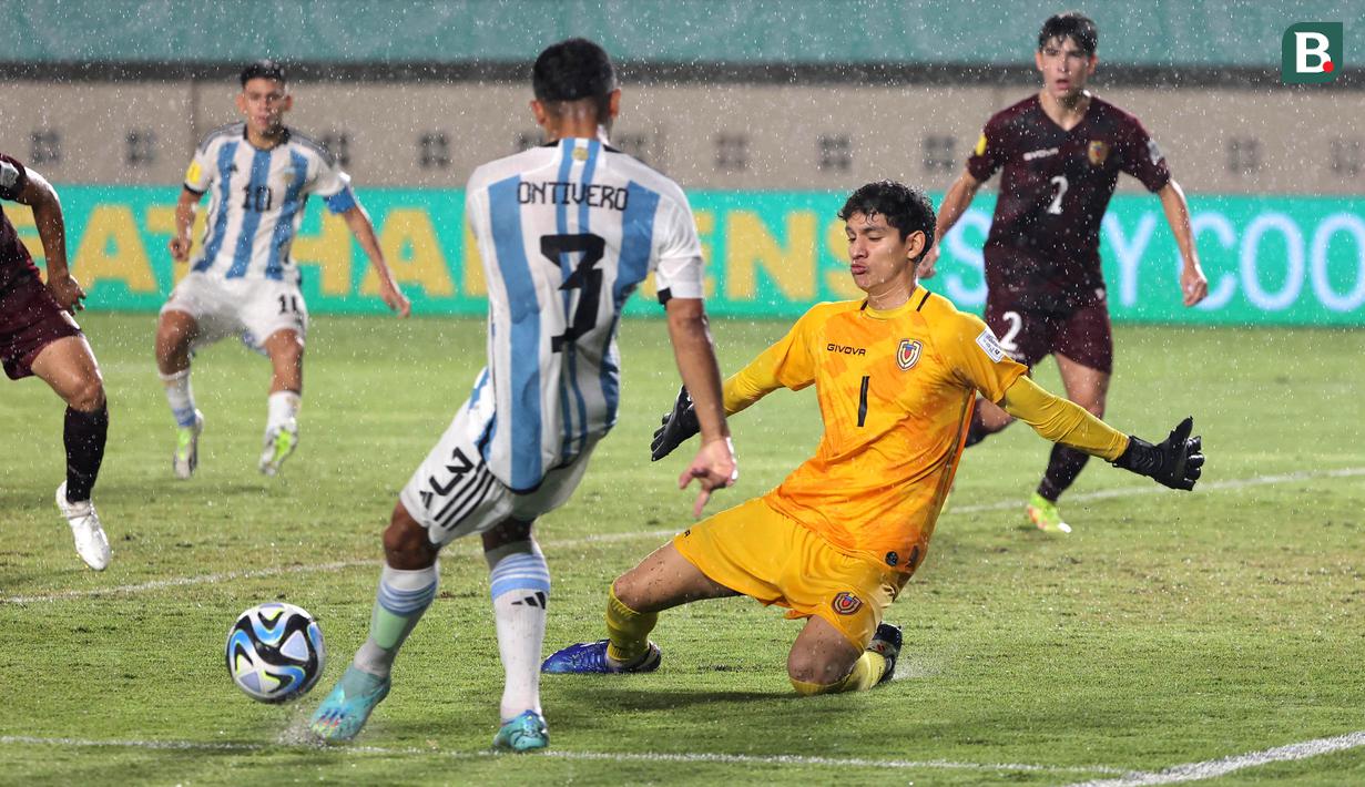 <p>Kiper Timnas Venezuela U-17, Jorge Sanchez, berusaha menghalau tendangan dari pemain Timnas Argentina U-17, Octavio&nbsp;Ontivero, pada laga 16 besar Piala Dunia U-17 2023 di Stadion Si Jalak Harupat, Bandung, Selasa (21/11/2023). (Bola.com/Ikhwan Yanuar)</p>