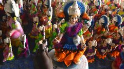 Seorang perajin mengecat patung dewi Hindu Lakshmi di sebuah lokakarya menjelang Diwali, festival lampu Hindu di pinggiran Hyderabad (28/10/2021). Diwali merupakan festival cahaya yang dianggap banyak orang sebagai awal tahun baru. (AFP/Noah Seelam)