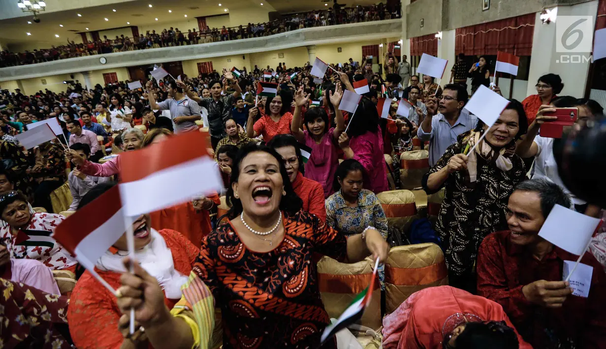 Jemaat mengibarkan bendera merah putih dan Palestina dalam acara Natal Taruna Merah Putih di Jakarta, Jumat (22/12). Perayaan natal tersebut sebagai bentuk kepedulian terhadap kedaulatan Palestina. (Liputan6.com/Faizal Fanani)
