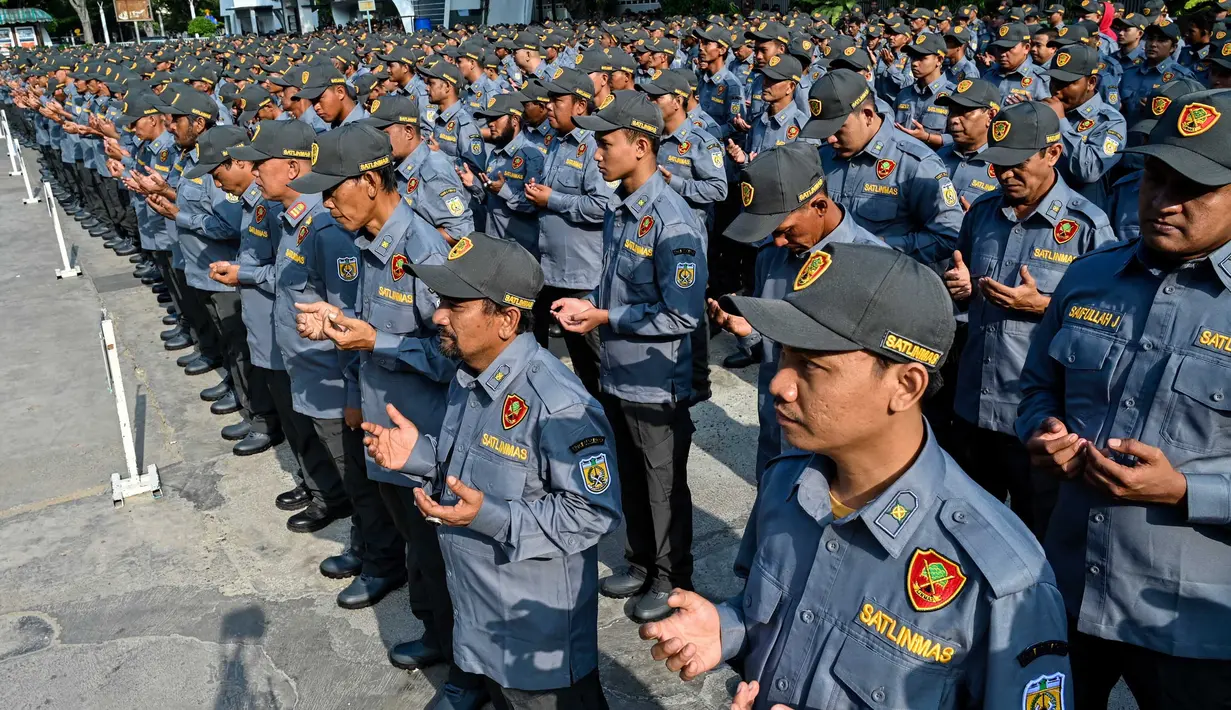 Anggota satuan perlindungan masyarakat (LINMAS) berdoa saat mengikuti apel pengamanan pemilu di Banda Aceh pada 8 Februari 2024. (CHAIDEER MAHYUDDIN/AFP)