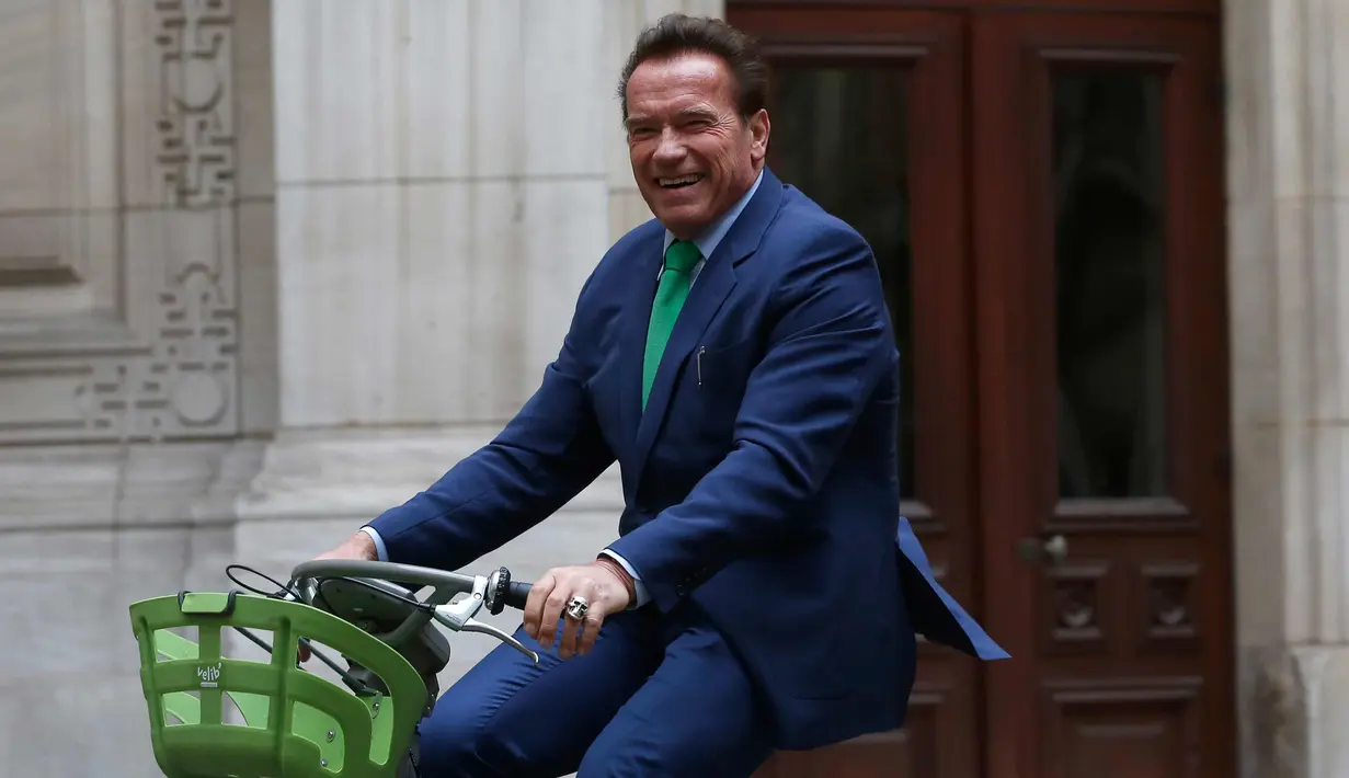 Gubernur California ke-38, Arnold Schwarzenegger tersenyum saat mengendarai sepeda untuk bertemu Walikota Paris, Anne HIdalgo di Paris (11/12). Schwarzenegger berada di Paris untuk menghadiri pertemuan puncak iklim One Planet. (AP Photo / Thibault Camus)