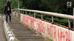 Warga melintasi jembatan layang Jalan HR Rasuna Said, Jakarta, Selasa (11/7). Dinding pembatas jembatan layang HR Rasuna Said arah kuningan dipenuhi coretan. (Liputan6.com/Helmi Fithriansyah)