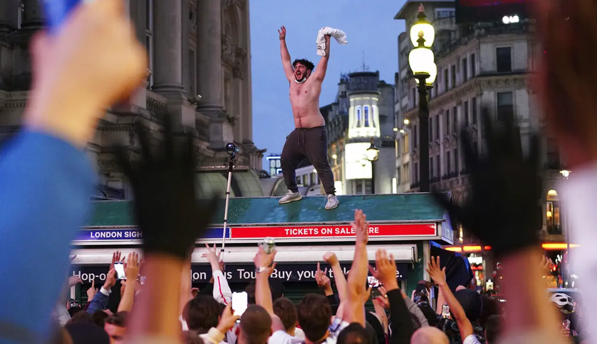 Suporter Inggris di Piccadilly Circus merayakan kemenangan Inggris atas Jerman pada pertandingan babak 16 besar Euro 2020 di London, Inggris, Selasa (29/6/2021). Inggris menang 2-0.(Yui Mok/PA via AP)