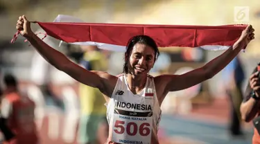 Atlet Lompat Jauh Indonesia, Maria Natalia Londa membawa bendera Merah Putih usai berlaga di nomor triple jump putri SEA Games di Stadium Bukit Jalil, Malaysia, Rabu (23/8). (Liputan6.com/Faizal Fanani)