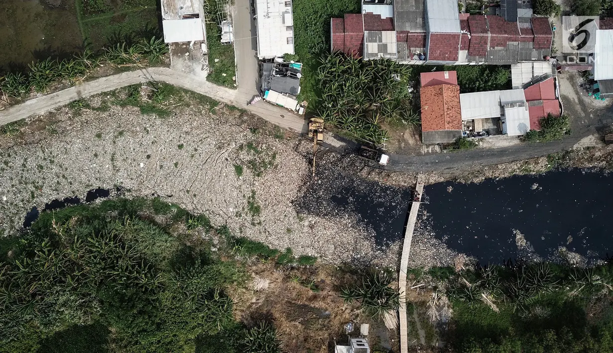 Pantauan dari udara, alat berat mengeruk sampah yang menutupi Kali Pisang Batu, Tarumajaya, Bekasi, Rabu (9/1). Sampah rumah tangga yang diduga dari aliran kali di wilayah Kota Bekasi  dikeluhkan warga karena bau tidak sedap. (Liputan6.com/Fery Pradolo)
