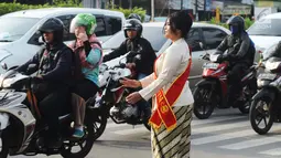 Personel Polisi Wanita (Polwan) Polres Jakarta Timur mengenakan pakaian kebaya saat mengatur arus lalu lintas di Jalan Otista Raya, Jatinegara, Jumat (20/4). Para polwan itu juga mengenakan selempang bertulisan Polres Jaktim. (Merdeka.com/Imam Buhori)