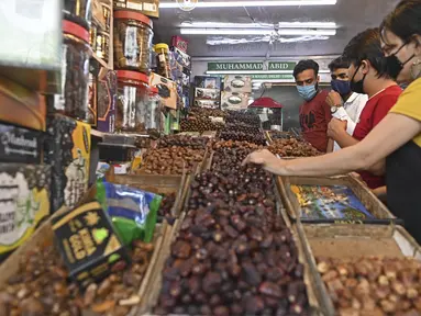 Orang-orang membeli kurma dari toko di sepanjang jalan menjelang bulan suci Ramadhan di Delhi, India pada Selasa (13/4/2021). Kurma sangat identik dengan bulan Ramadhan, karena buah yang satu ini kerap dijadikan pengisi menu sahur dan berbuka puasa. (Sajjad HUSSAIN / AFP)