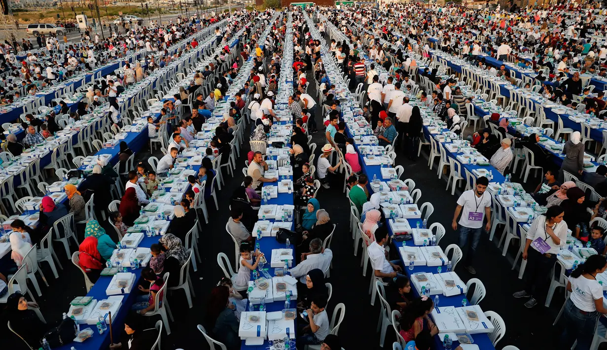 Ribuan orang yang terdiri dari warga Lebanon beserta yatim piatu dan pengungsi Suriah  berkumpul di sekitar meja-meja Iftar di Beirut Waterfront, Lebanon (9/6). Buka puasa bersama ini diikuti oleh 5.400 orang. (AP Photo / Hussein Malla)