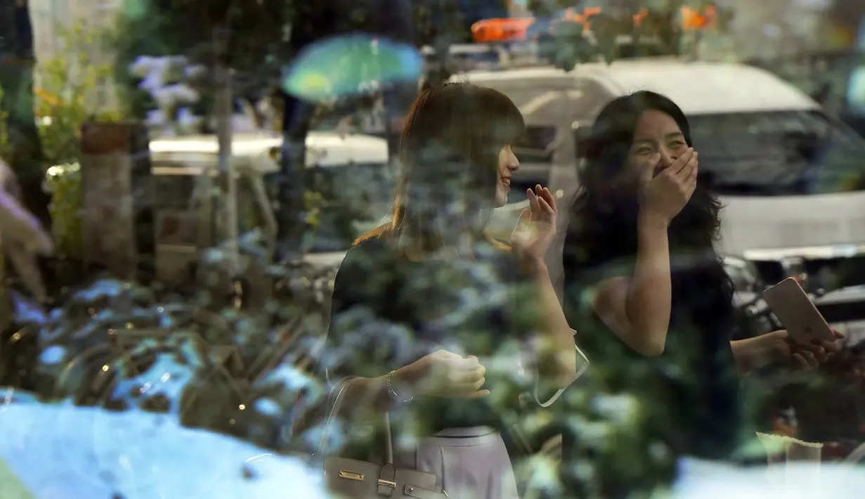 Dua gadis tertawa terlihat dari cermin ketika mereka di jalan Nagoya, Jepang (24/9/2019). Nagoya merupakan kota pertama di Jepang yang memiliki pusat perbelanjaan di bawah tanah. (AP Photo/Christophe Ena)