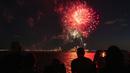 Orang-orang menyaksikan kembang api meledak di atas Pelabuhan New York dan Patung Liberty di New York, Selasa (15/6/2021). New York menandai berakhirnya pembatasan COVID-19 dengan perayaan kembang api di seluruh negara bagian untuk menghormati para kelompok pekerja penting. (AP Photo/Craig Ruttle)