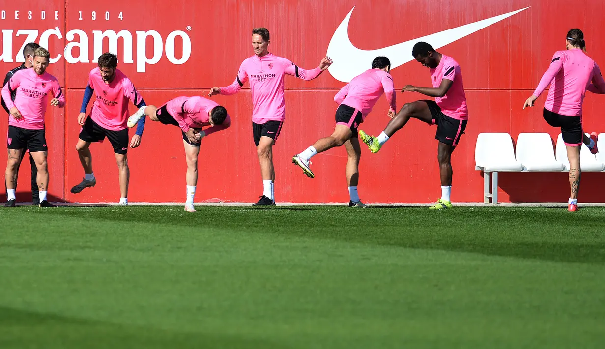 Para pemain Sevilla melakukan pemanasan selama sesi latihan tim di Ciudad Deportiva Jose Ramon Cisneros Palacios,  Spanyol (16/2/2021). Sevilla akan bertanding melawan Borrusia Dortmund pada leg pertama babak 16 besar Liga Champions di Estadio Ramón Sánchez Pizjuán. (AFP/Cristina Quicler)