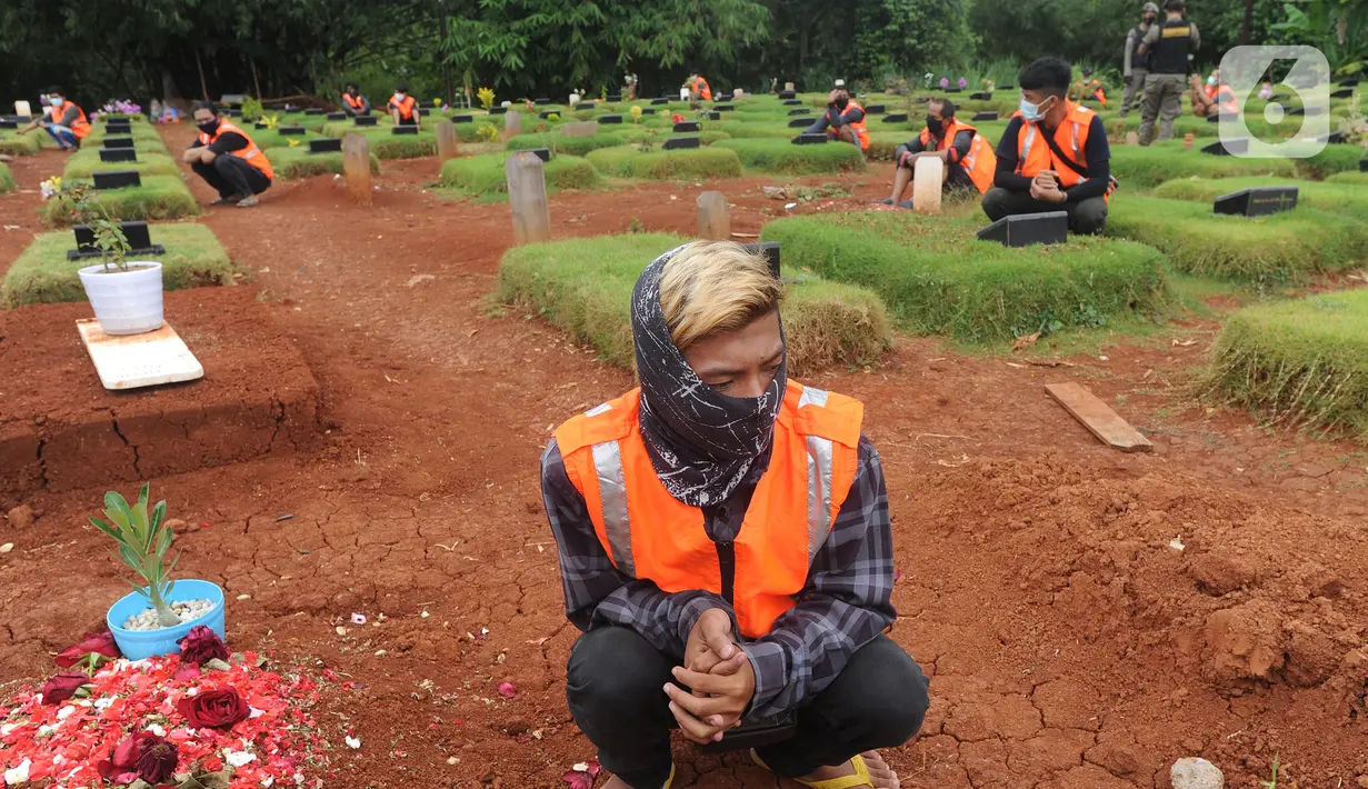 Sejumlah pelanggar PSBB berdoa di makam korban Covid-19 di TPU Jombang, Tangerang Selatan, Senin (18/1/2020). Petugas Satpol PP bersama Polres Tangsel memberikan hukuman bagi 17 pelanggar PSBB yang terkena razia masker di kawasan Bintaro. (merdeka.com/Arie Basuki)