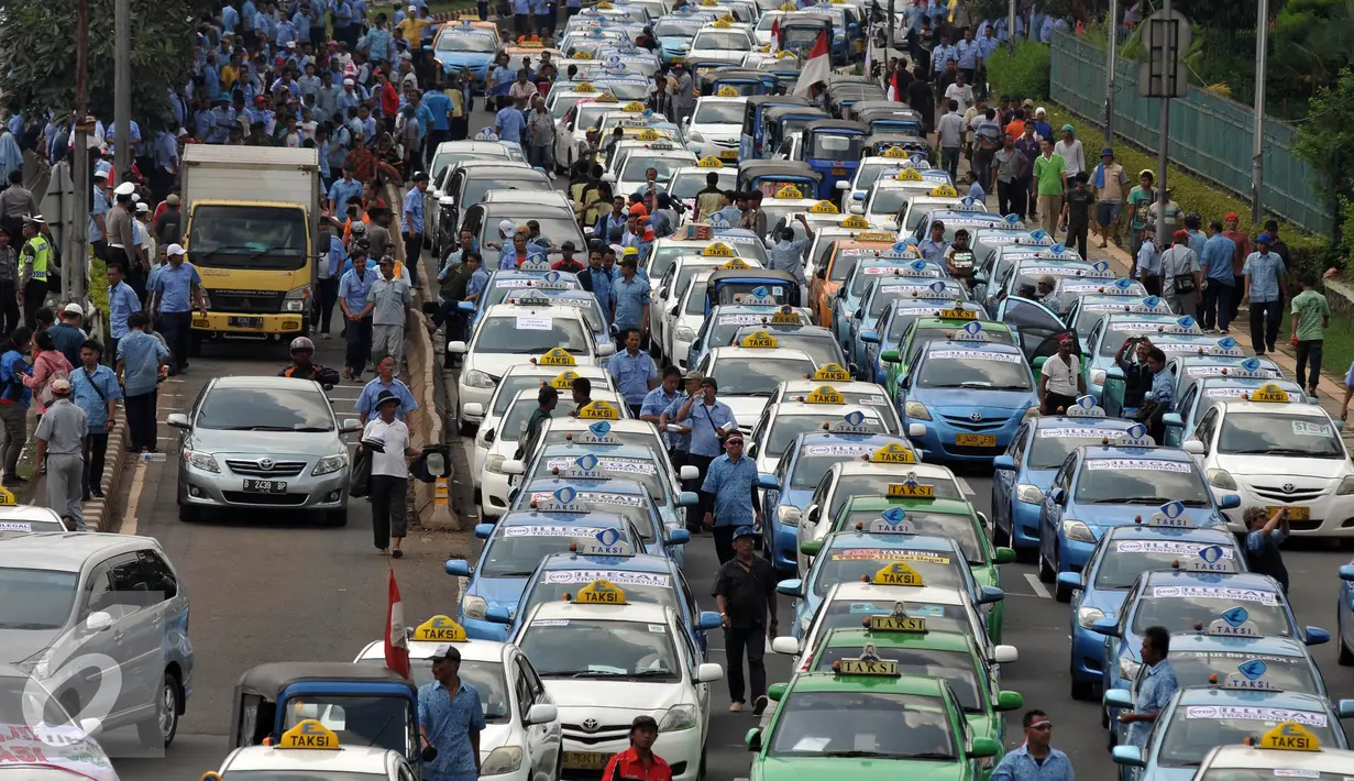 Sejumlah Sopir taksi saat melakukan demo di sepanjang jalan tol Gatot Subroto, Jakarta, Selasa (22/3). Selain melakukan demo supir taxi tersebut melakukan sweeping ke sopir taksi yang beroperasi di dalam tol, dan membakar ban.(Liputan6.com/Johan Tallo)