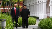 Suasana saat Presiden AS Donald Trump (kiri) dengan Pemimpin Korea Utara Kim Jong-un berjalan di taman Hotel Capella, Pulau Sentosa, Singapura, Selasa (12/6). Trump dan Kim optimis bahwa KTT akan sukses. (Anthony Wallace/Pool/AFP)