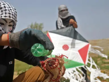 Warga Palestina menyiapkan bom molotov untuk diterbangkan menggunakan layang-layang di atas pagar perbatasan dengan Israel, di pinggiran timur Kota Gaza (20/4). Unjuk rasa warga Palestina terhadap Isrel memasuki minggu keempat. (AFP Photo/Mohammed Abed)