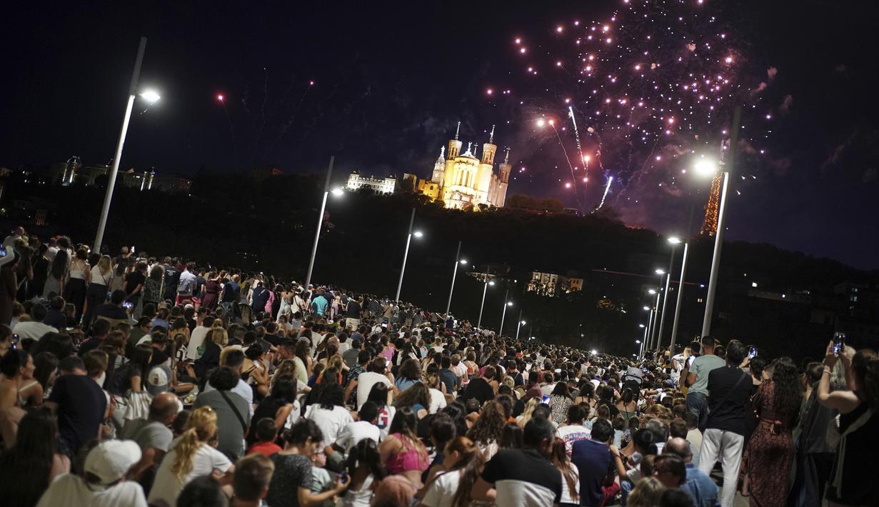 Orang-orang berkumpul di jembatan untuk menyaksikan kembang api Hari Bastille di Lyon, Prancis tengah, Jumat, 14 Juli 2023. (AP Photo/Laurent Cipriani)