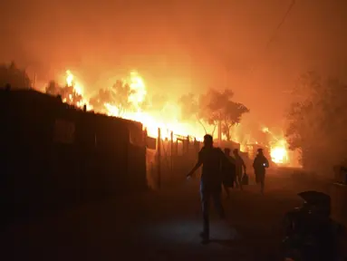 Pengungsi dan migran lari saat api membakar di kamp pengungsi Moria di timur laut pulau Aegean Lesbos, Yunani, Rabu (9/9/2020). Kamp tersebut digunakan sebagai tempat penampungan bagi para pengungsi dan imigran pencari suaka. (AP Photo/Panagiotis Balaskas)