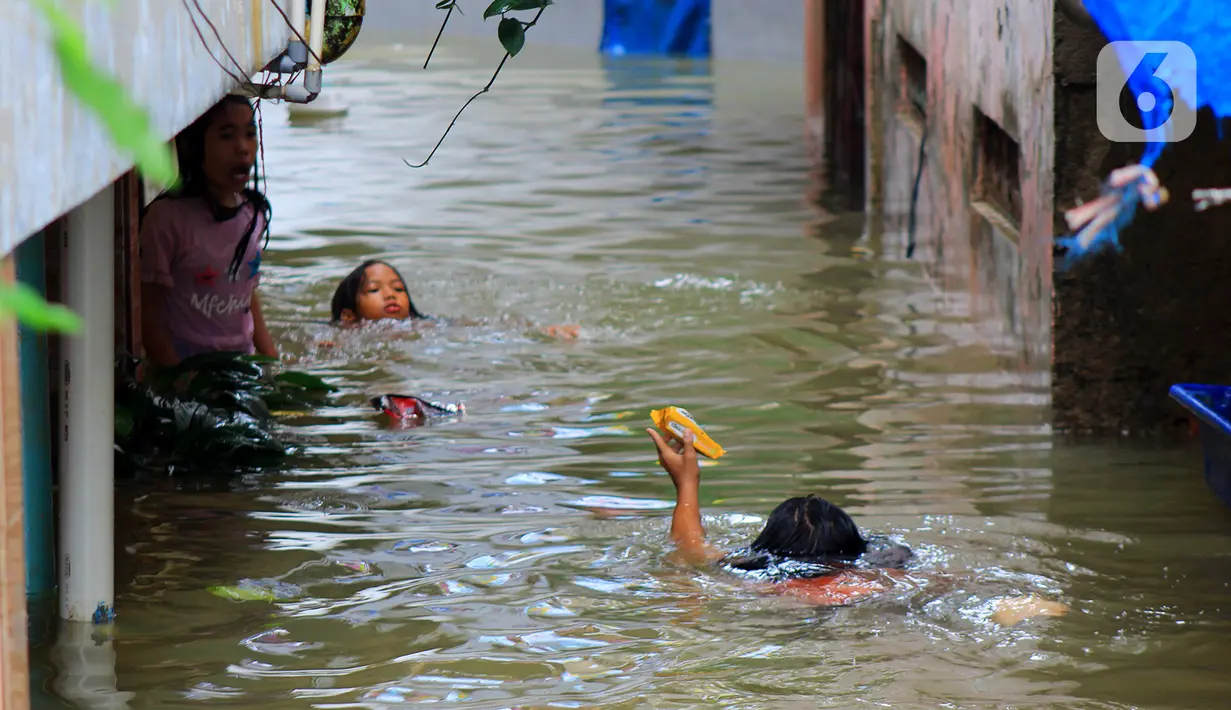 Sejumlah anak bermain banjir yang merendam kawasan Kampung Melayu Kecil, Bukit Duri, Jakarta, Selasa (25/2/2020). Banjir tersebut akibat luapan sungai Ciliwung. (merdeka.com/magang/ Muhammad Fayyadh)