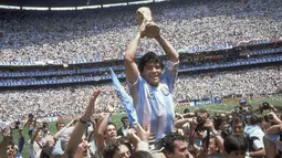Penyerang Argentina, Diego Maradona, mengangkat trofi Piala Dunia saat usai mengalahkan Jerman Barat pada laga final Piala Dunia 1986 di Meksiko, (29/6/1986). (Photo by - / AFP)