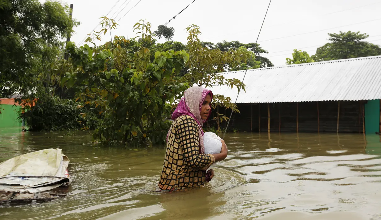 Seorang wanita menerjang banjir di Sunamganj, Bangladesh, Minggu (12/7/2020). Banjir di sejumlah wilayah Bangladesh telah memengaruhi kehidupan lebih dari 1,3 juta orang dan mengakibatkan puluhan ribu keluarga mengungsi. (Xinhua)