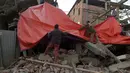 Warga menggunakan terpal untuk menutup bangunan yang rusak di Imphal setelah gempa bumi 6,7 SR mengguncang timur laut India, Senin (4/1). Delapan orang tewas sementara lebih dari 100 orang menderita luka-luka akibat gempa. (AFP PHOTO/Dibyangshu Sarkar)