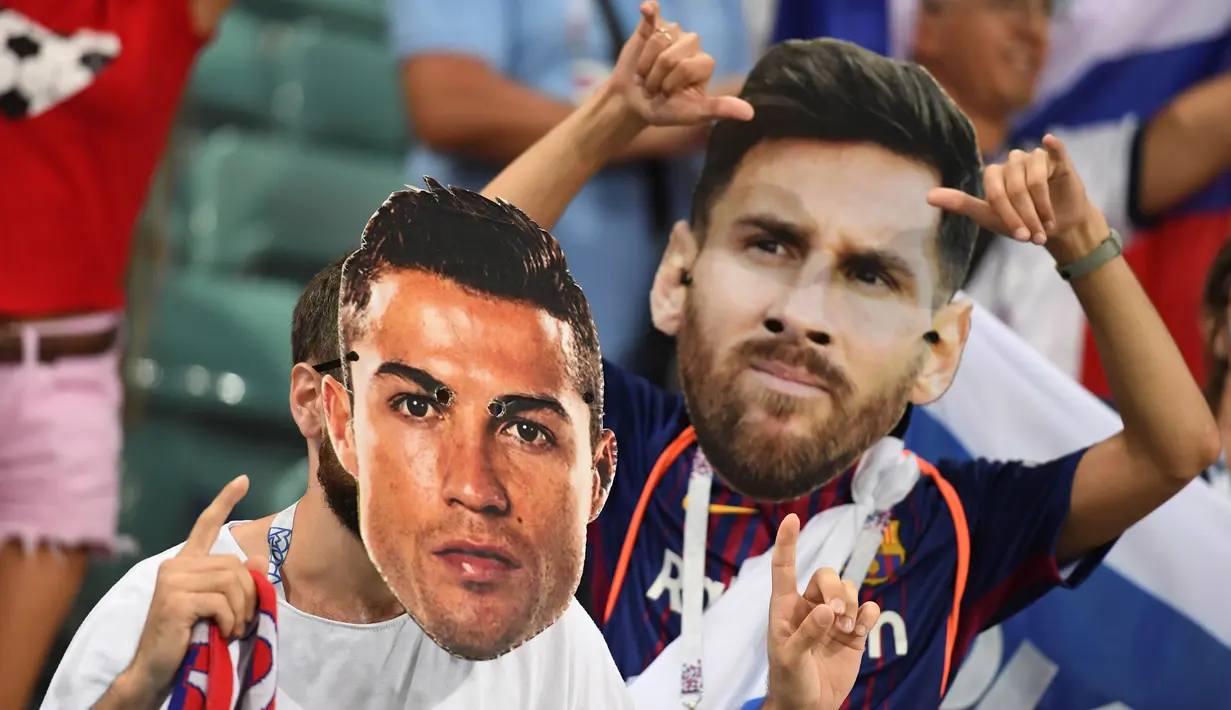 Suporter berpose memakai topeng bintang Portugal, Cristiano Ronaldo dan bintang Argentina, Lionel Messi sebelum laga babak perempat final Piala Dunia 2018 antara Rusia dan Kroasia di Stadion Olimpiade Fisht, Sabtu (7/7). (AFP PHOTO/Kirill KUDRYAVTSEV)