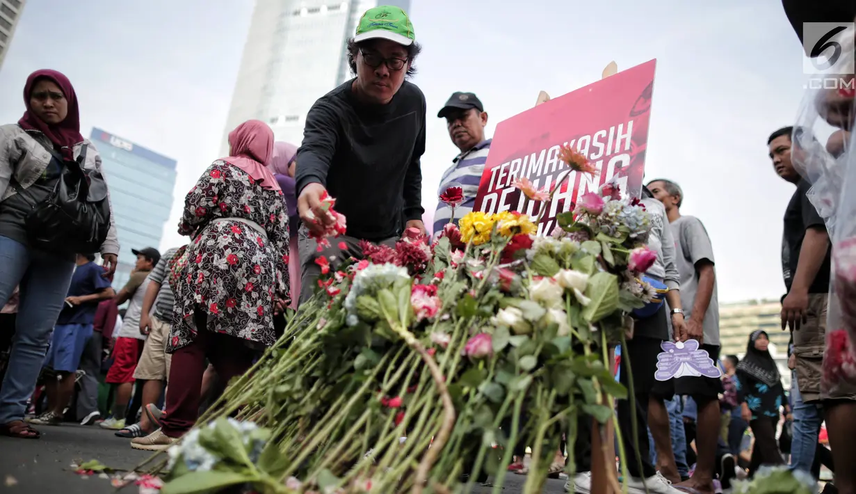 Pengunjung car free day menaburkan bunga di atas papan bertuliskan "Terima Kasih Pejuang Demokrasi" di Bundaran HI, Jakarta, Minggu (28/4/2019). Kegiatan tabur bunga tesebut sebagai bentuk belasungkawa atas meninggalnya petugas KPPS dalam Pemilu 2019. (Liputan6.com/Faizal Fanani)