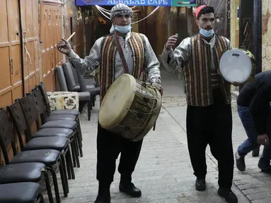 Pria Palestina yang dikenal dengan "Musaharatis" saat bertugas sebagai "penabuh drum Ramadhan" di kota tua Hebron, Tepi Barat pada 14 April 2021. Mereka menyusuri jalan-jalan kota, masuk ke gang-gang kecil untuk membangunkan umat Islam sahur selama bulan Ramadhan. (HAZEM BADER/AFP)