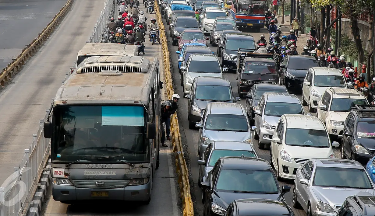 Dua pemotor menengok di belakang Transjakarta saat razia sterilisasi jalur Transjakarta di kawasan Mampang, Jakarta, Jumat (25/9/2015). Setiap harinya banyak pemotor yang nekat memasuki lajur busway yang semestinya steril. (Liputan6.com/Faizal Fanani)