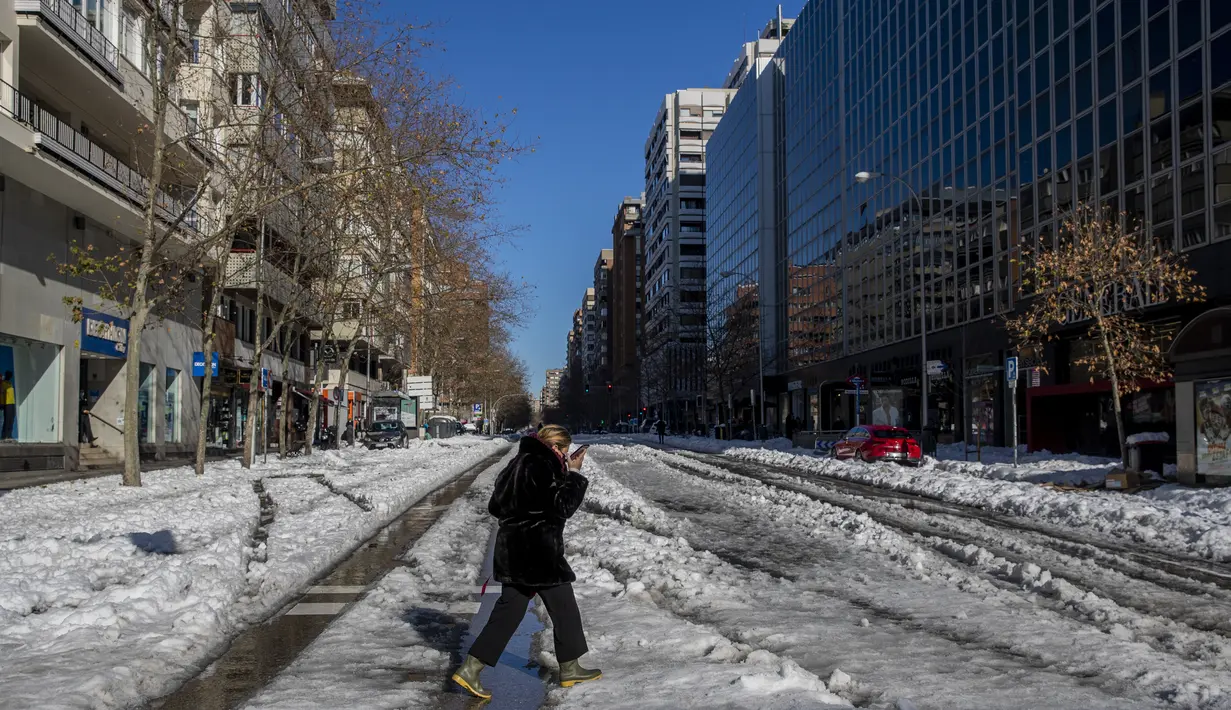 Seorang perempuan berjalan melewati salju di Madrid, Spanyol, Senin (11/1/2021). Ibu kota Spanyol itu berusaha bangkit kembali setelah menghadapi badai salju terburuk dalam 50 tahun terakhir yang melumpuhkan sebagian besar wilayah Spanyol tengah selama akhir pekan. (AP Photo/Manu Fernandez)