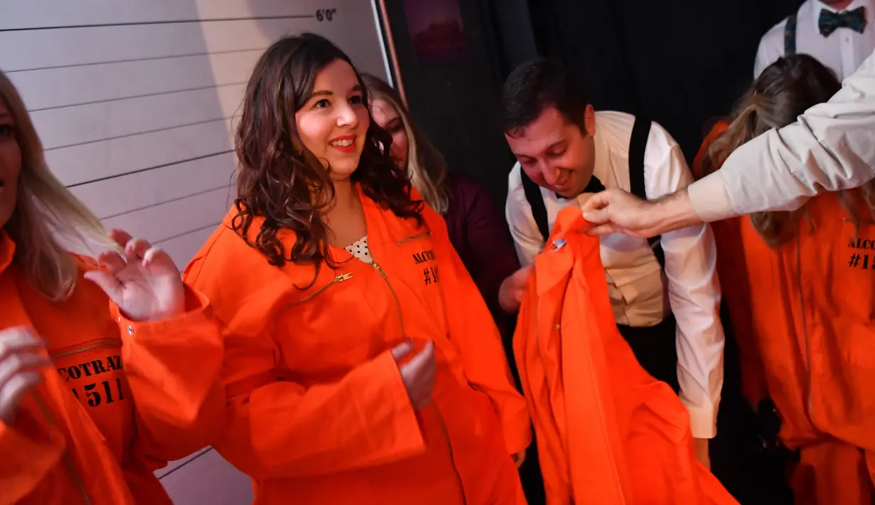 Pengunjung diberikan baju tahanan saat tiba di bar koktail Alcotraz, London , 11 Oktober 2018. Bar berkonsep penjara ini terinspirasi dari karya fiksi terkenal, Shawshank Redemption dan serial Netflix bertajuk 'Orange Is a New Black'. (BEN STANSALL / AFP)