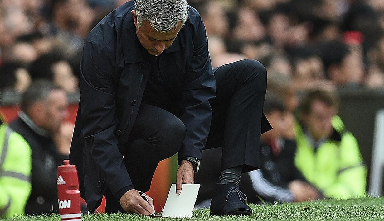 Pelatih Manchester United,  Jose Mourinho tengah mencatat hal-hal penting selama pertandingan melawan Manchester City pada laga Premier League di Old Trafford, Manchester,  (10/9/2016). (AFP/Oli Scarff)