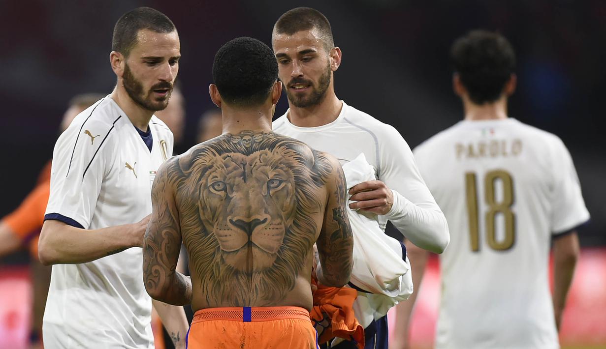 Penyerang Belanda, Memphis Depay, bertukar baju dengan gelandang Italia, Leonardo Spinazzola. Dalam pertandingan tersebut Italia berhasil menciptakan lima kesempatan, sedangkan Belanda memperoleh empat tendangan tepat sasaran. (AFP/John Thys)
