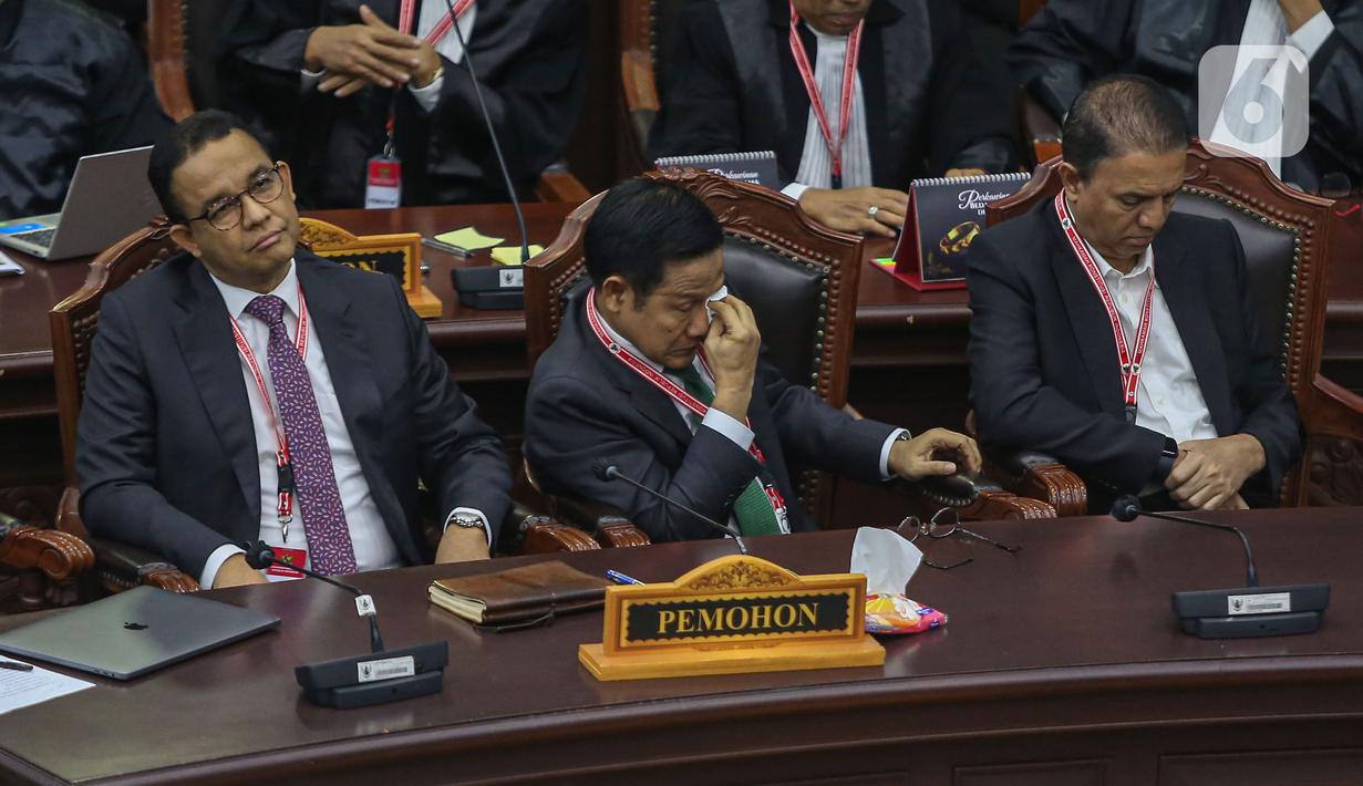 Calon wakil presiden nomor urut 1 Muhaimin Iskandar mengusap wajahnya dengan tisu di sebelah calon presiden Anies Baswedan saat mengikuti jalannya sidang putusan perselisihan hasil Pilpres 2024 di Gedung Mahkamah Konstitusi (MK), Jakarta, Senin (22/4/2024). (Liputan6.com/Angga Yuniar)