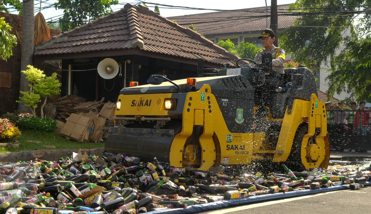 Polisi menggunakan alat berat saat memusnahkan ribuan botor miras di Polres Kota Tangerang Banten, Rabu, (23/12).Polresta Tangerang memusnahkan miras sebanyak 11.155 botol dan 264 Ciu yang berkemas botol mineral. (Liputan6.com/Faisal R Syam)